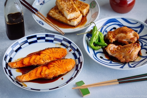 Teriyaki Tofu, Teriyaki Salmon, and Teriyaki Chicken served each on a Japanese plate seasoned with homemade Teriyaki Sauce.