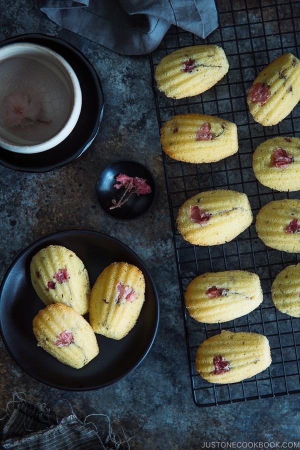 Cherry Blossom Madeleines on a wire rack and a small black plate.