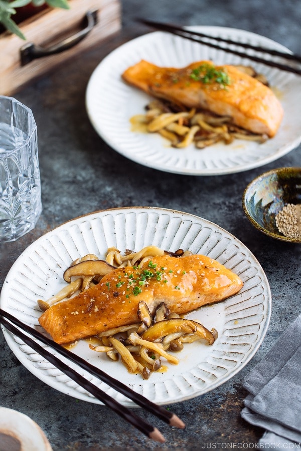 White plate containing Miso Butter Salmon served with sauteed shiitake and shimeji mushrooms.