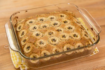 banana bread in a square glass container on cutting board