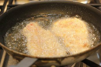 breaded pork slices frying in a pan
