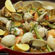 Paella with chicken thighs, squid, shrimps, manila clams, and asparagus in a pot.
