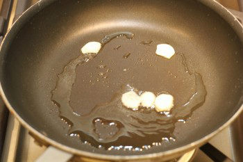 garlic cooking in oil in a frying pan