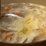 a ladle skimming foam off soup in a pot