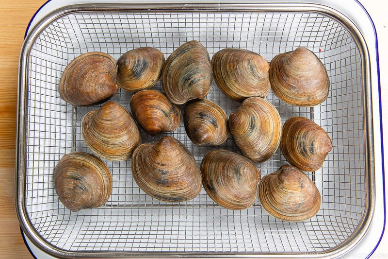 Clams being cleaned over a wire rack.