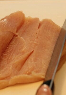 a piece of chicken fillet by knife