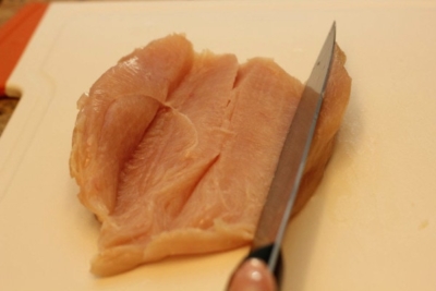 a piece of chicken fillet by knife