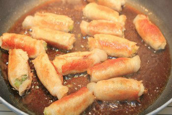 pork rolls cooking in seasoning on a frying pan