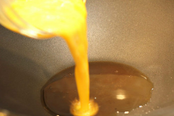 egg pouring into a wok with oil