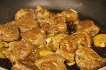 teriyaki pork balls cooking in a frying pan with seasoning