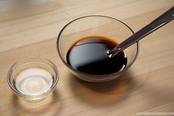 teriyaki sauce ingredients in 2 glass bowls on top of cutting board