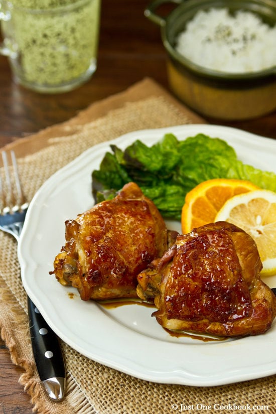 Chicken Adobo with green salad on a white plate.