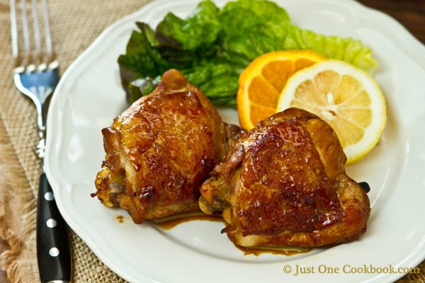 Chicken Adobo with green salad on a white plate.