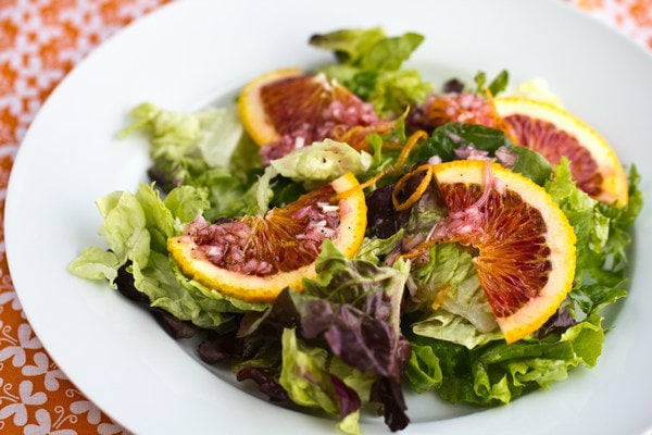 Green Salad with Blood Orange Vinaigrette on a white plate.
