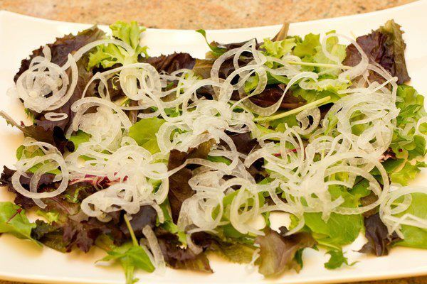 smoked salmon salad with sliced onion on top of white plate