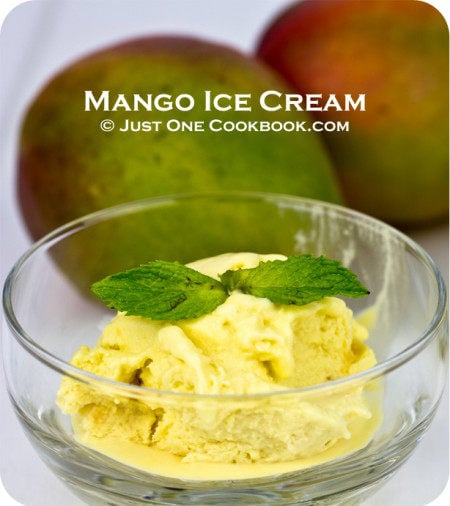 Mango Ice Cream in a glass cup and mangoes on a side.