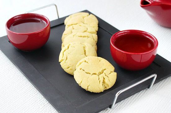 Green tea cookies on a plate with cups of tea.