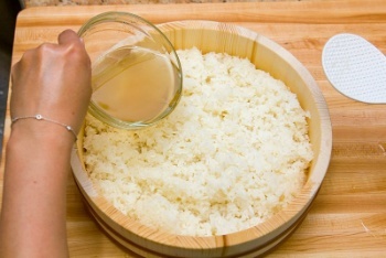 pouring vinegar solution on rice in a wooden container