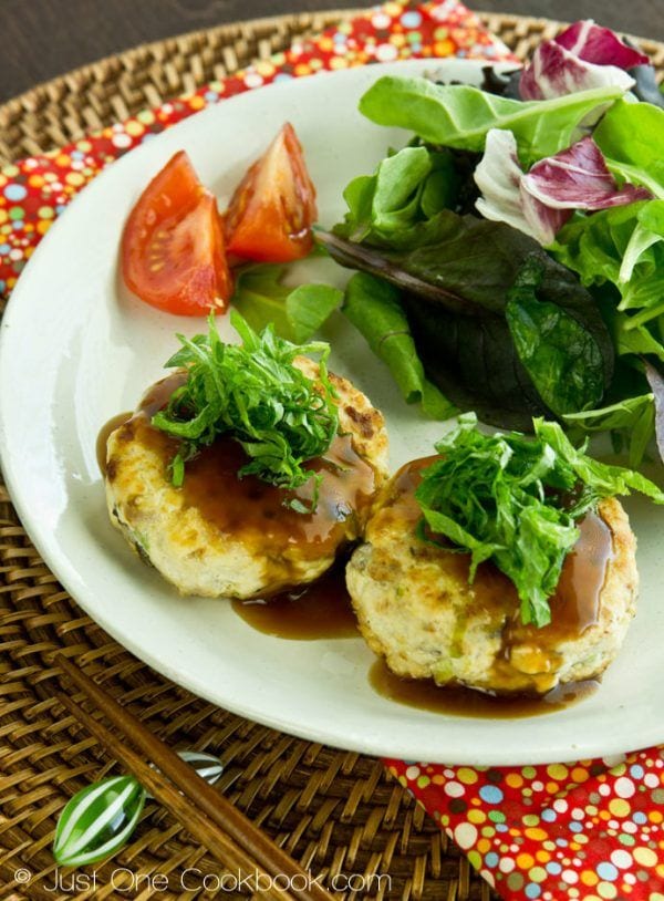 Chicken & Tofu Hamburger Steak topped with shiso and soy glaze, and salad on a white plate.