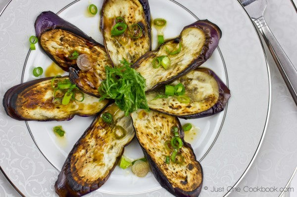 Eggplant with Sesame Ponzu Sauce topped with shio and green onion on a plate.