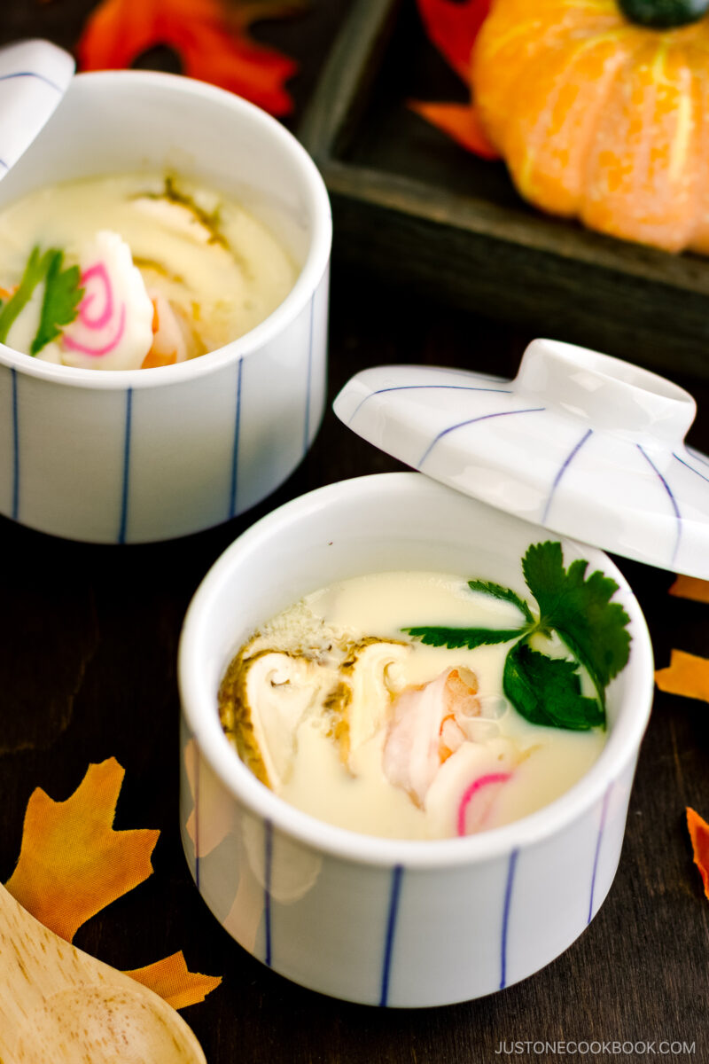 Chawanmushi cups containing matsutake mushrooms, shrimp, and fish cake slices in a savory steamed egg mixture.