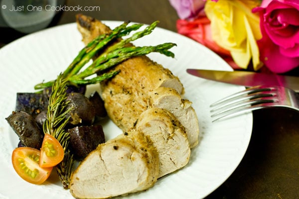 Thomas Keller's Brined Pork Tenderloin with potatoes and asparagus on a white plate.