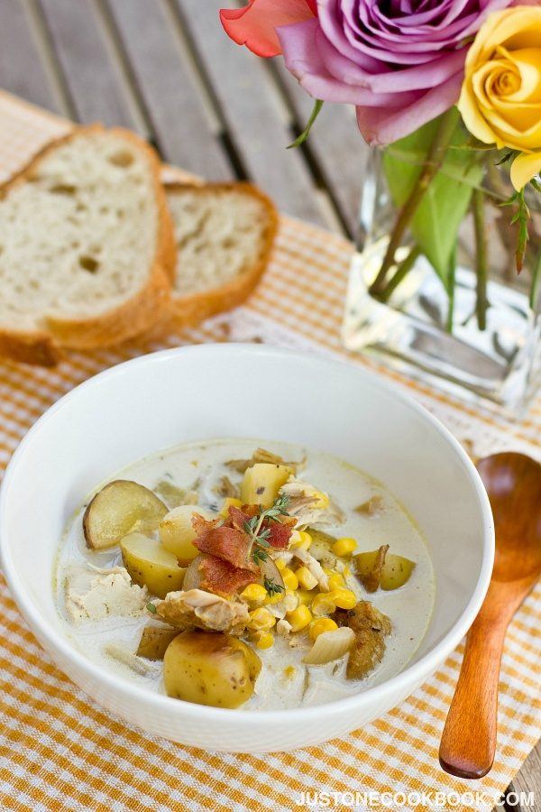 Chicken Corn Chowder in a white soup bowl and sliced breads on the table.