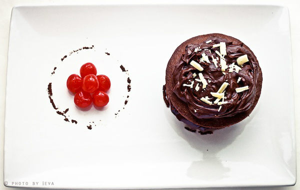 Chocolate Cake with candied cherry on a plate.