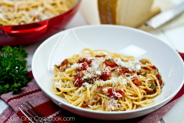 Tomato Bacon Pasta topped with cheese on a white plate.