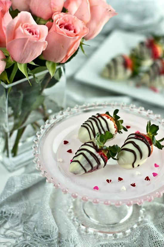 Chocolate Covered Strawberries on a cake stand and pink rose.