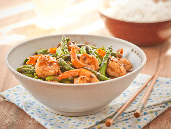 Stir Fried Shrimp & Asparagus in a bowl and steamed rice on a side.