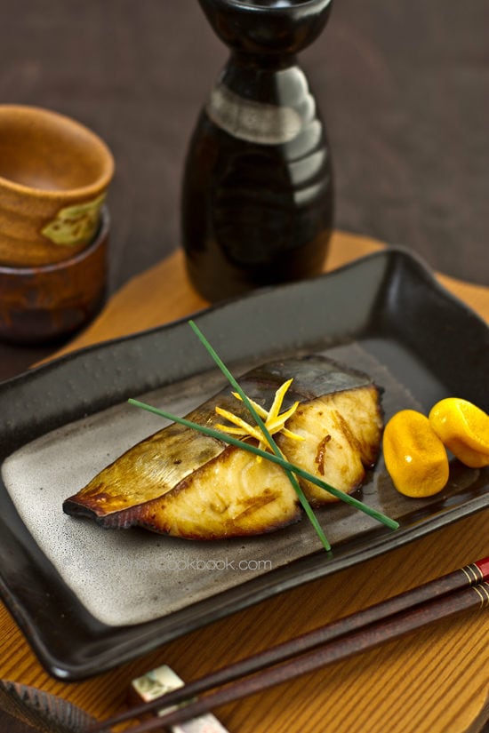 Spanish Mackerel with Yuzu on a black plate.