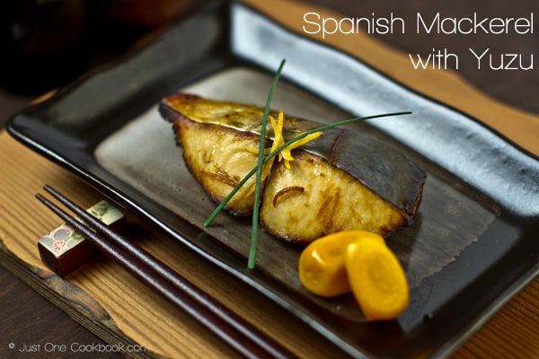 Spanish Mackerel with Yuzu on a black plate.