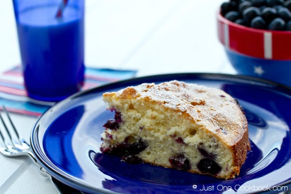 Blueberry Cake on a blue plate and a blue cup of milk on a table.
