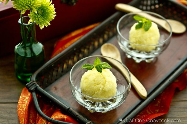 Pineapple Sorbet in glass cups and spoons on a wooden tray.