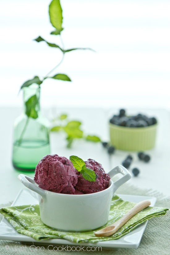 Blueberry Frozen Yogurt in a white cup on a white table.