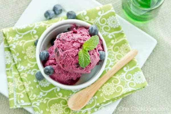 Blueberry Frozen Yogurt with mint leave and blueberry in a white cup.
