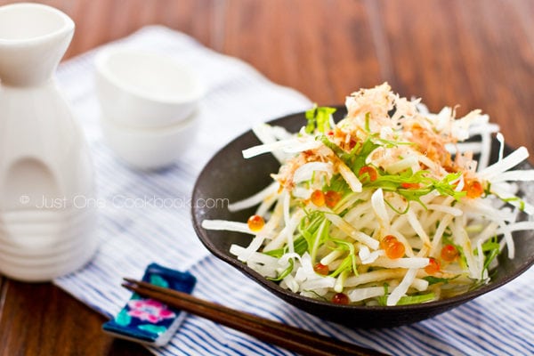 Daikon Salad and sake bottle on a table.