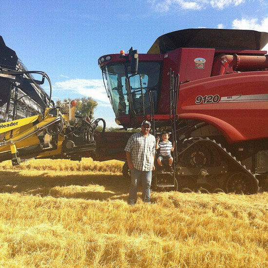 a boy and a man in front of a harvester in a field