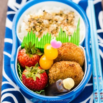 Korokke Bento with rice, tomatoes and fruit.