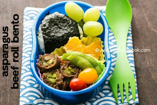 Asparagus Beef Roll Bento with onigiri, edamame, tomato and fresh fruit.