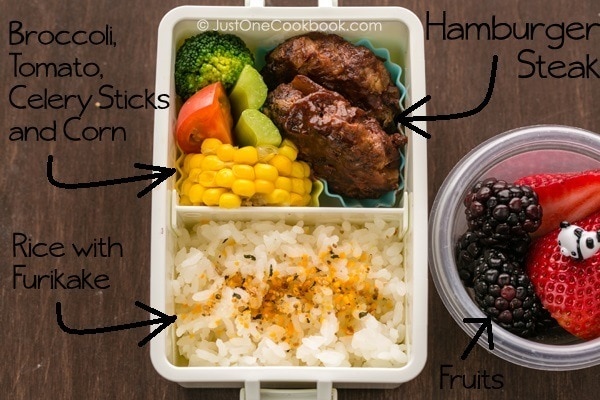 Hamburger Steak Bento and fresh fruit on a table.