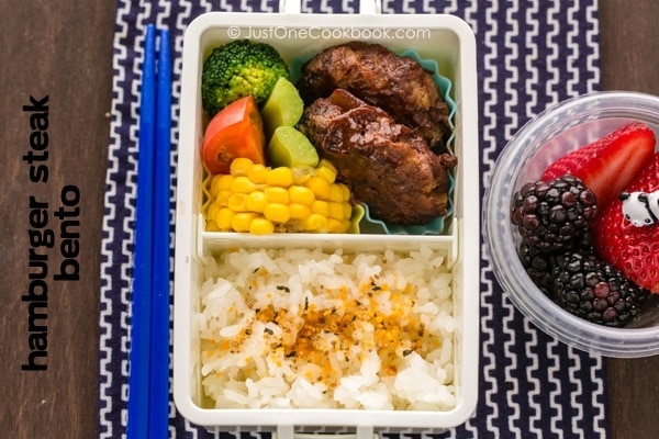 Hamburger Steak Bento and fresh fruits on a table.