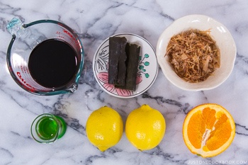 Ponzu Sauce Ingredients containing kombu, lemon, bonito flakes, mirin, and soy sauce.