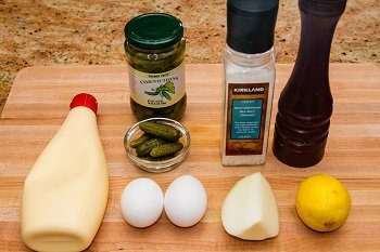 ingredients for tartar sauce including eggs, onion, lemon, pickles, mayo, salt, pepper