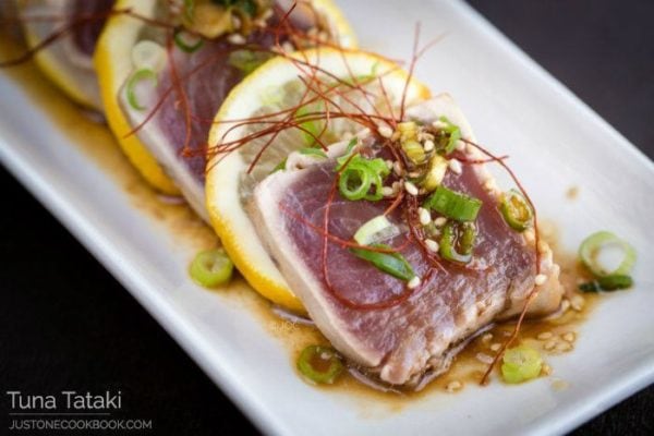 Tuna Tataki and sliced lemons on a plate.