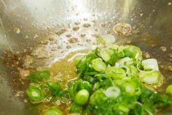 green onion stir fry in a metal pan