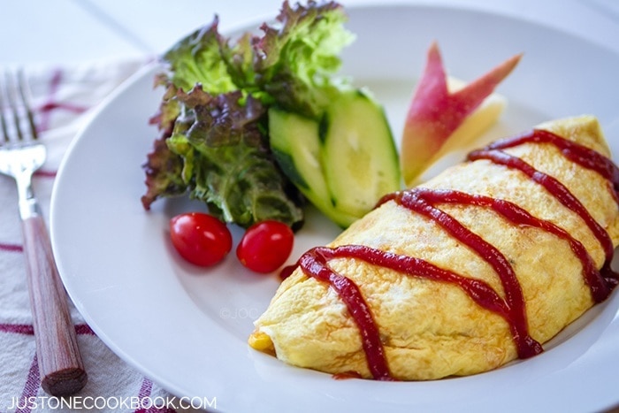 Omurice, Japanese Omelette Rice and salad on a white plate.