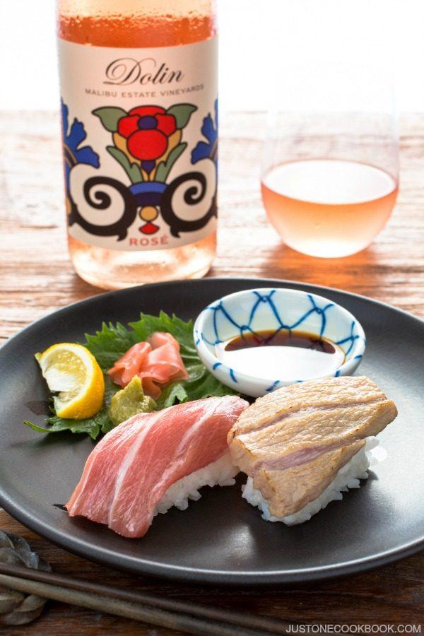 Otoro Sushi on a plate and bottle of drink with glass.