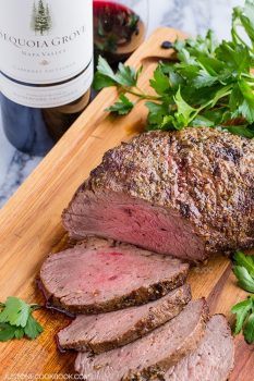 Smoked Tri Tip on a cutting board and bottle of wine on a table.